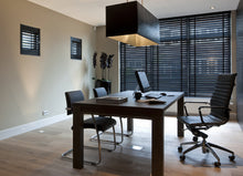 Load image into Gallery viewer, A well-lit interior room featuring a wooden desk with chairs around it, including a swivel chair, with Venetian blinds on the windows.